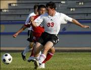Lawrence High soccer player Greg Payne (33) moves the ball against Vienney Phiomavong during a scrimmage at Haskell Stadium. The Lions' varsity squared off against the school's JV team during the school's Jamboree on Wednesday.