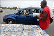 Frederick Chambers hands a Yellow Pages phone book to Delmer Archer Aug. 1 at a phone book distribution center in Chalmette, La. With nearly half the city's population gone, two books have shrunk to one.