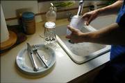 Gaylen Garinger, who lives southwest of Lawrence, does some dishes in his sink with the only water avalible which is heavy with salt and unpalatable.