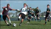Free State High midfielder Andrew Heck (9) chases a loose ball with Shawnee Mission South goalkeeper Chris Marx, left. The Firebirds lost, 4-1, Tuesday at Free State.