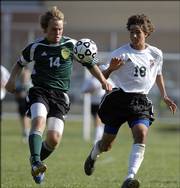 Free State High forward Erik Slan, right, and Shawnee Mission South defender Shane Shulze fight for a loose ball. The Raiders defeated the Firebirds, 4-1, Tuesday at Free State.