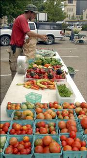 Avery Lominska sets out produce for customers at the Lawrence Farmers Market, 1020 Vt. He is the son of Bob Lominska, who continues gardening throughout fall.