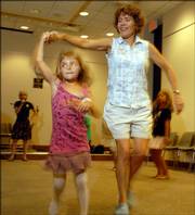 Tori Goldman, left, performs a turn with the assistance of Deborah Altus at the 10th anniversary celebration of the Lawrence Barn Dance Assn. The event was Aug. 26 at the Lawrence Public Library, 707 Vt.