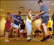 Carla Mumma and Jerry Jost, right, dance down the line of people at the 10th anniversary of the Lawrence Barn Dance Assn. The event was Aug. 26 at the Lawrence Public Library, 707 Vt.