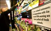 A sign informing customers that fresh spinach has been removed is displayed as customer Jeff Leider sorts through other packaged salad mixes at Mollie Stone's Tower Market in San Francisco. With at least one dead and dozens sickened across 19 states, health officials focused on California as the source of spinach contaminated by E. coli and grocers cleared the vegetable from their shelves.
