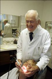 Dr. Paul Kincaid, 85, who has been a dentist in Lawrence for more than 60 years, demonstrates using an oral camera to view Janell Hoffman's teeth. Kincaid still practices part-time at the clinic where his son now is a dentist.