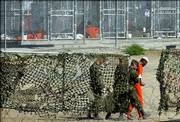 A detainee is escorted to interrogation by U.S. military guards at Camp X-Ray at Guantanamo Bay U.S. Naval Base, Cuba, in this March 1, 2002, file photo. Guantanamo received its first prisoners from Afghanistan in January 2002. A total of 770 detainees were sent there; its population today of Afghans, Arabs and others stands at 455.