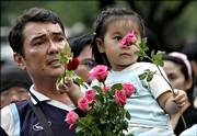 A Thai man brings his young daughter to hand out roses to soldiers involved in the military coup in Bangkok, Thailand. Army chief Gen. Sondhi Boonyaratkalin, who led the coup ousting Prime Minister Thaksin Shinawatra, told a news conference that he would act as prime minister for two weeks until a new leader "who is neutral and upholds democracy" is found. The new government would not hold on to power for more than a year, he said.