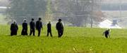 An Amish family walks across a field to attend the viewing for two of the five girls killed in Monday's attack at the West Nickel Mines Amish School in Nickel Mines, Pa. Funerals for four of the girls will be conducted today.