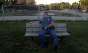 Adam Hoover, a Douglas County Sheriff's deputy, sits on a bench just south of the Boardwalk Apartments, where three people were killed a year ago today. Hoover lived in one of the buildings that burned and lost all of his belongings.