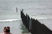 Raul Gomez, 35, and Lourdes Rolan, 36, kiss at a park overlooking the border wall in May in Tijuana, Mexico. This section of the border wall separating Tijuana and San Diego runs into the Pacific Ocean.