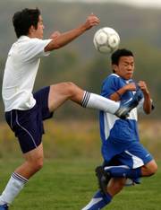 Seabury academy's aaron chung, left, heads down the field controlling the ball as K.C. Sumner's Yovanni Rojas tries to stay out of the way.