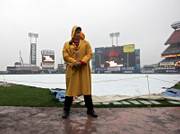 Security guard Howard Broad stands in the rain at Shea Stadium before Game 1 of the National League championship series was postponed on Wednesday in New York.