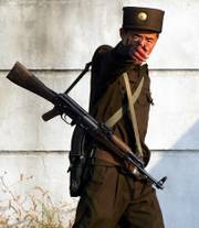 A North Korean soldier reacts to a photographer on a passing boat Thursday in the North Korean town of Sinuiju, opposite the Chinese border city of Dandong. The U.S. on Thursday began pushing for a U.N. resolution that adds a travel ban on North Korea, while South Korea said it detected no abnormal levels of radioactivity after the North's claimed nuclear test.