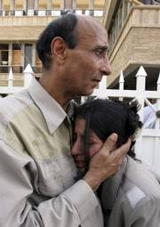 Employees with the Shaabiya television station comfort each other in front of the station's building in Baghdad. About two dozen gunmen pulled up Thursday at the station in seven cars, stormed quickly into the offices and opened fire, killing 11 station employees.