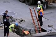 Port Authority police officers, left, watch as a worker inspects an object he pulled from a hole in the pavement at ground zero in New York. Searchers who have yet to unearth more than half the underground sites apparently overlooked during the initial excavation of ground zero have found more than 100 pieces of human remains believed to belong to Sept. 11 victims.