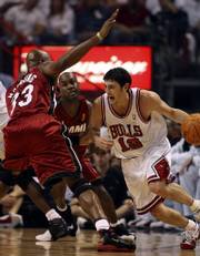 Chicago guard Kirk Hinrich (12) drives past Miami Heat center Alonzo Mourning (33) and guard Gary Payton. The former Kansas University standout scored 26 points - and a five-year, $47.5 million contract extension - Tuesday. The Bulls pummeled the defending champions, 108-66.