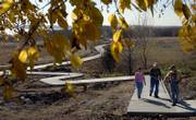 Walking a new extension of bike and hike trails Thursday at Clinton Lake, from left, are Nancy Goodwin, Topeka, her father, Virgil Reese, Tecumseh, and Nancy's husband, Mike Goodwin. Mike, Clinton Lake Trail coordinator, has been working with the Corps of Engineers and the city of Lawrence to extend the Lawrence bike and hike trail another 2/3 mile to the base of Sanders Mound Vista, visible at upper center of photograph.