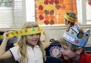 Nicole Super, 5, left, with Connor Apel, 6, right, and Andre Painter, 6, background, try on paper headbands for the annual Thanksgiving Day play put on by their kindergarten class at Kettering Elementary School in Long Beach, Calif. For years, students in this class have not been adding feathers to their American Indian headbands because they are considered sacred objects in American Indian cultures.