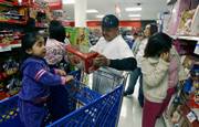 Ashley Miranda, 3, left, observes as her mother Leslie Marin, second from left, and a friend, Fernando Lucas, third from left, shop for toys during a Thanksgiving Day sale at Kmart in Los Angeles. Some stores aren't waiting for Black Friday to kick off the holiday shopping frenzy.