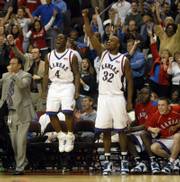 Kansas University's Sherron Collins (4) and Darnell Jackson (32) fly off the bench following a KU bucket in overtime. The Jayhawks defeated Florida, 82-80 in overtime, Saturday in Las Vegas.