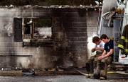 Anderson volunteer firefighters Adam Murphy, left, and Brandon Hines, rest on their truck after helping put out a fire at the Anderson Guest House, a group home for elderly and mentally ill, where 10 people died early Monday, Nov. 27, 2006, in Anderson Mo.