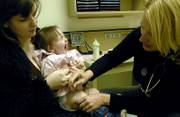 Lawrence resident Linda McLaughlin holds her 1-year-old daughter, Charlie, as she receives a series of one-year immunization shots from public health nurse Cori Green on Tuesday afternoon at the Lawrence-Douglas County Health Department. Kansas improved its national ranking on childhood immunizations in 2006.