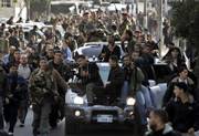 Palestinian security force officers and gunmen carry their weapons as they ride on the top of vehicles during the funeral for three sons of senior intelligence officer Baha Balousheh. The children were killed Monday in a drive-by shooting attack in Gaza City. The slayings were part of an apparent botched assassination attempt that could ignite widespread factional fighting.