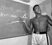 A young Muhammad Ali points to a sign he wrote in his dressing room before his fight against Archie Moore in Los Angeles, in this Nov. 15, 1962, file photo predicting he&squot;d knock Moore out in the fourth round, which he did. The sign also predicts Ali will be the next champ via a knockout over Sonny Liston in eight rounds. "Ali Rap: Muhammad Ali the First Heavyweight Champion of Rap," proclaims Ali&squot;s verbal barrage was the beginning of hip-hop.