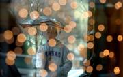 Viewed through the holiday decorations at Silver Works, 715 Mass., Lawrence native Darren Field, Lakewood, Colo., makes his way down Massachusetts Street during Wednesday showers. Despite the rain, many shoppers kept to the task.