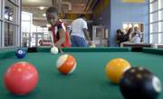 Corey Banks, 11, takes aim at a striped ball during a game of pool at the East Lawrence Recreation Center, 1245 E. 15th St. With more than 10 days off from school for winter break, Corey has divided his time between family gatherings and activities with friends at the youth center. He shot pool Tuesday.