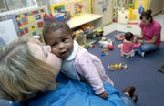 Terionna McIntyre, 5 months, gets a kiss from Robin Barber, director of Kindercare Learning Center, 2333 Crestline Drive, Thursday afternoon in the infant room of the center as Jasmy Mavilla, 9 months, plays with teacher Whitney Blake. The center is one of several in Lawrence that offer child care.