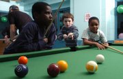 Stephan Fulton, 10, lines up his shot as he plays a game of pool with Dachae Atkins, 9, left, and his cousin Kendrick Atkins, 7, right, during an overnight New Year's party for local children at the Holcom Park Recreation Center, 2700 W. 27th St. Kids ages 5-12 enjoyed games, pizza, and various other activities during the all-night party.