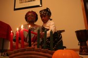 Maren Turner of Lawrence explains the meaning behind Kwanzaa traditions as Kalia Fowler, 6, lights the ceremonial candles. Turner welcomed nine guests for a Karamu feast to celebrate Kwanzaa on Sunday night at her home.