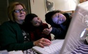 Anna Spitz plays at the computer with her adopted Chinese daughters Sarah, center, and Rachel at their home in Tucson, Ariz. With China putting tighter restrictions on adoptions, effective next spring, single adults like Spitz no longer will be able to adopt children from China.