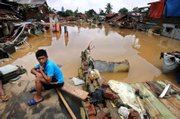An Indonesian boy sits amid the ruins of houses destroyed by flooding in Jakarta, Indonesia. Boats ferried emergency supplies to desperate residents of Indonesia's flood-stricken capital Monday as overflowing rivers again burst their banks following days of rain.