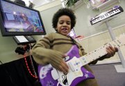 Jalen Stewart demonstrates the I Can Play Guitar System from Fisher-Price during the American International Toy Fair last week in New York. The lead guitar plugs into a television and contains the software necessary for the interactive learning and playing experience. It will retail for $99.99 in July. Fisher-Price is a division of Mattel.