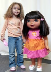 Model Bailey Bass, 3, poses with a life-sized Dora from Fisher-Price. Squeeze the hand of the 34-inch-tall doll, and she can respond with phrases in Spanish and English.