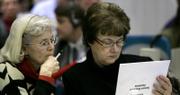 State Board of Education members Kathy Martin, left, and Sally Cauble look over new evolution-friendly science standards for Kansas public schools during a board meeting in Topeka. The board voted 6-4 on Tuesday to adopt new science standards that eliminate language about intelligent design. The intelligent design concept holds that life is so complex that it must have been created by a higher authority.
