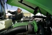 Farmer Vance Ehmke looks at the engine in a new tractor earlier this month at a John Deere dealership in Leoti. With higher crop prices and a break in drought conditions, many farmers are in the market for new equipment.