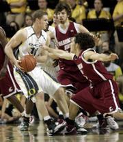 Oregon's Maarty Leunen, left, looks for room against Washington State's Derrick Low, right, and Robbie Cowgill. Oregon won, 64-59, on Thursday night in Eugene, Ore.