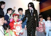 Michael Jackson poses for a photograph with a group of Japanese children from a Tokyo orphanage invited specially for an exclusive fan event Thursday in Tokyo. Jackson is currently in Japan to host the meet-and-greet party and a fan art contest today.