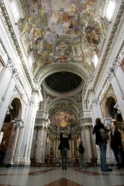 Visitors study the ceiling of St. Ignatius Loyola Church, in central Rome. The magnificent churches of the city center serve more as museums than houses of prayer, while many among the burgeoning throngs of the faithful in the scrappy outskirts of town are forced to worship in garages, former grocery stores or prefab buildings.