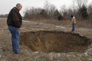 Murray Balk, left, and Randy Johnson measure a 30-feet wide sinkhole caused by undermining in Rick Schultz's field in Southeast Kansas. Abandoned sub-surface coal mines are collapsing, causing sinkholes and large ground collapses that often times lead to voids hundreds of feet deep throughout the tri-state mining district in southeast Kansas.