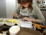 Kazumi Shimomura prepares a "bento," or lunchbox, for her 6-year old son Nao at her home in Ichihara, east of Tokyo. Shimorura slices cheese to decorate rice in the shape of a dinosaur based on a sketch drawn by her son. Shimomura is one of a growing group of women transforming the traditional Japanese box lunch for kids and husbands into a painstaking work of art.
