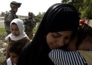 A woman leads her children past U.S. army soldiers from the 1st Battalion, 23rd Infantry Regiment on Wednesday in western Baghdad's Sunni neighborhood of Ghazaliyah, Iraq. U.S. troops conducted a major house search in parts of Ghazaliyah Wednesday.