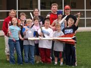 Eudora High School students from the Aerospace Alliance stand with some third- through eighth-graders who attended a rocket-building workshop on Saturday. The students display a model rocket along with the rockets they made at the workshop.