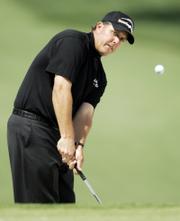 Phil Mickelson chips to the seventh green during the first round of the Masters. Mickelson, the defending champion, shot a 4-over-par 76 on Thursday in Augusta, Ga., that left him seven shots out of the lead.