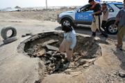 Iraqis examine a crater after a roadside bomb struck a British patrol Thursday in Basra, Iraq. The patrol struck a roadside bomb and was hit by small-arms fire, British military spokeswoman Capt. Katie Brown said.