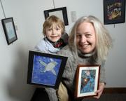 Sara Stalling and her son Maya Spitzer, 6, are part of an art exhibit at the Lawrence Public Library gallery that includes artwork they have done together and individually. Maya holds a piece that he and his mother worked on together called "There is a Bird in the Sky"; Stallings holds a mixed-media piece of hers titled "Tsunami."